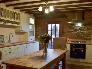 a kitchen with a table with a vase of flowers on it at Ivy Cottage in South Wingfield