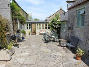 a patio with chairs and tables and a building at The Tack Room - Uk30438 in Kingsbury Episcopi