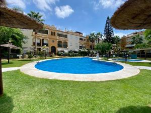een groot blauw zwembad in het midden van een tuin bij Villa palacio Playa y piscina Grupo AC Gestion in Cádiz