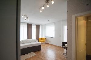 a bedroom with a bed and a yellow chair at Hotel Garni am Arbach in Eningen unter Achalm