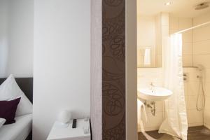 two images of a bathroom with a sink and a toilet at Hotel Garni am Arbach in Eningen unter Achalm +14 photos