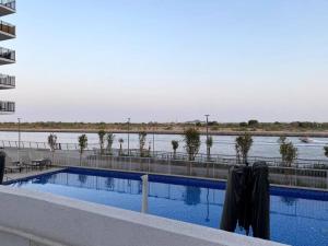 een zwembad naast een waterlichaam bij Brand New 1 Bedroom, Vacation Home! in Abu Dhabi