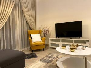 een woonkamer met een tv en een gele stoel bij Brand New 1 Bedroom, Vacation Home! in Abu Dhabi