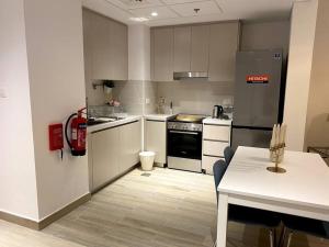 een keuken met een fornuis, een koelkast en een tafel bij Brand New 1 Bedroom, Vacation Home! in Abu Dhabi