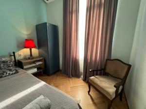 een slaapkamer met een bed, een stoel en een raam bij Lola Apartments in Tbilisi City