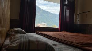 Bett in einem Zimmer mit einem großen Fenster in der Unterkunft YOLO Backpackers MAX - Manali in Manali