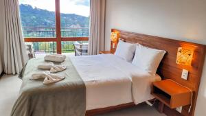 Cama en habitación de hotel con ventana grande en Chalés Mirante Monte Verde en Monte Verde