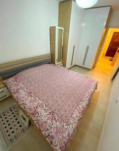 a small bedroom with a bed with a pink bedspread at 1-Bedroom Apartment Fushë Kosovë in Kosovo Polje