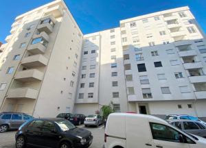 two tall buildings with cars parked in a parking lot at 1-Bedroom Apartment Fushë Kosovë in Kosovo Polje