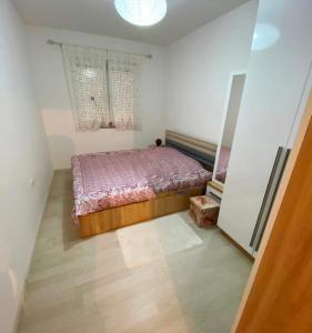 1-Bedroom Apartment Fushë Kosovë في Kosovo Polje: غرفة نوم بسرير ولحاف بنفسجي