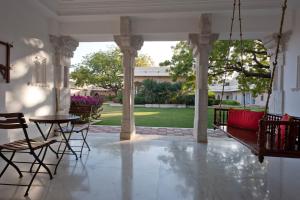 a porch with a swing and a table and chairs at Sardargarh Heritage Fort Udaipur in Sardārgarh