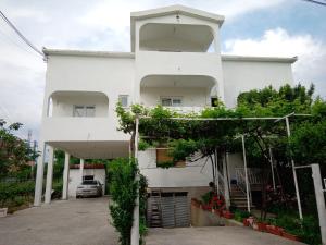 biały budynek apartamentowy z parkingiem w obiekcie Hostel Olea w mieście Podgorica