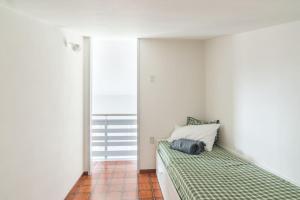 a white bedroom with a bed with a green blanket at Garda Friends Apartments in Toscolano Maderno