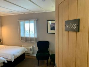 a bedroom with a bed and a chair and a window at Lochindaal Hotel in Port Charlotte
