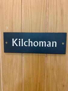 a blue sign on a wooden door with the word kittoglobin at Lochindaal Hotel in Port Charlotte