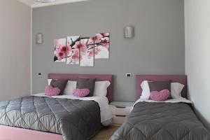 duas camas num quarto cor-de-rosa e cinzento em B&B Vesuvio Smiling em Ercolano