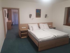 Schlafzimmer mit einem Bett mit weißer Bettwäsche und Kissen in der Unterkunft Penzion Vilma in Smilovice