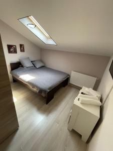a small bedroom with a bed and a skylight at Apartament 2 camere in Chiajna