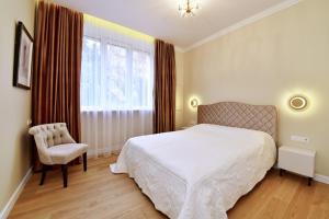 a bedroom with a bed and a chair and a window at Luxury Central Apartment in Putvinskio street in Kaunas