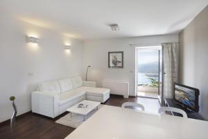 a living room with a white couch and a tv at Casa M Rabac in Rabac