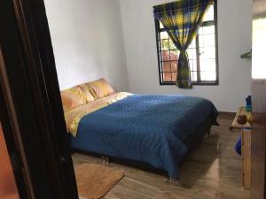 una camera da letto con un letto con un piumone blu e una finestra di Casa en la Montaña a Macanal