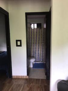 a bathroom with a toilet and a door to a room at Casa en la Montaña in Macanal