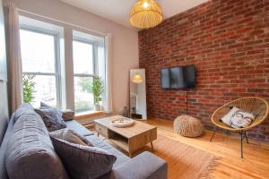 a living room with a couch and a brick wall at ZEN - SelfCheckIn - Rooftop - Terraces - St-Denis in Montréal