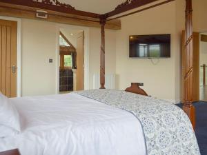 a bedroom with a white bed with a tv on the wall at The Grange in Dinmore