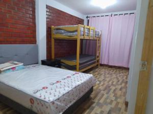een slaapkamer met een stapelbed en een bakstenen muur bij CASA PLAYA REFUGIO AZUL in Cerro Azul