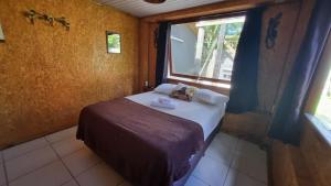 a small bedroom with a bed and a window at Arte da Tribo Hostel & Camping in Praia do Rosa