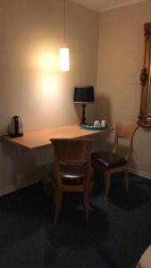 a room with a desk and two chairs and a lamp at Motel Lido in Bredebro