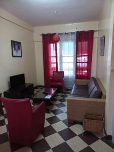 ein Wohnzimmer mit roten Vorhängen, einem Sofa und Stühlen in der Unterkunft Appartement sympathique Jules Ferry. in Dakar