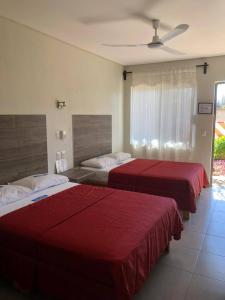 2 camas en una habitación de hotel con sábanas rojas en Hotel Guivá San Pablo, en Hacienda Blanca