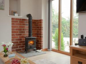 a living room with a brick fireplace and a stove at Daisy Cottage - Uk31294 