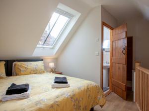 a bedroom with a bed with yellow sheets and a window at Daisy Cottage - Uk31294 