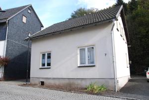 ein weißes Haus mit zwei Fenstern auf einer Straße in der Unterkunft Ferienwohnung Burgruine in Rauenstein