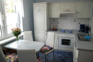 cocina con armarios blancos, mesa y sillas en Ferienwohnung Burgruine, en Rauenstein