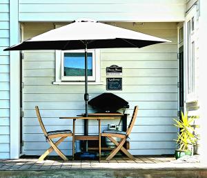 une table et deux chaises sous un parasol dans l'établissement Okauia House, Matamata, à Matamata