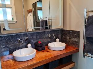 two sinks on a wooden counter in a bathroom at Okauia House, Matamata in Matamata