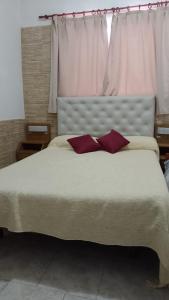 una camera da letto con un grande letto con due cuscini rossi di Hotel Atlantic a Mar de Ajó