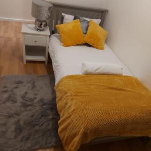 a bed with yellow pillows and a yellow blanket at Lovely 2-Bed Apartment in Milton Keynes in Milton Keynes