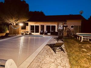 a swimming pool in front of a house at night at La Villa Perroquet in Poncins