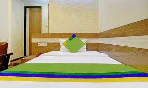 a bedroom with a bed with a green and yellow blanket at Treebo Trend Hiramani Parel Lalbaug in Mumbai