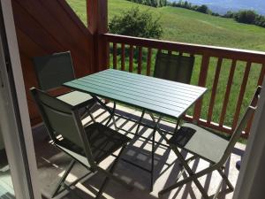 a green picnic table and two chairs on a porch at Appartement offrant une magnifique vue des montagnes in Saint-Léger-les-Mélèzes