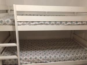 a white bunk bed with a patterned floor at Appartement offrant une magnifique vue des montagnes in Saint-Léger-les-Mélèzes