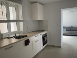 cocina con armarios blancos, fregadero y sofá en Résidence Casa Olea - Studio - T2 - T3 en Cauro