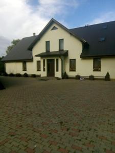 a white house with a black roof and a brick driveway at Vecais cels 25C in Jelgava