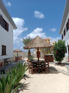 einen Tisch und Stühle mit Sonnenschirm am Strand in der Unterkunft Vilas na areia aparthotel in Sal Rei