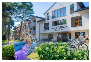 Neptuno Resort & Spa في دزيورزينو: امرأة تجلس على مرجيحة أمام الفندق