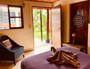 a bedroom with a bed and a chair and a window at Casa Flor de Vida in San Cristóbal de Las Casas